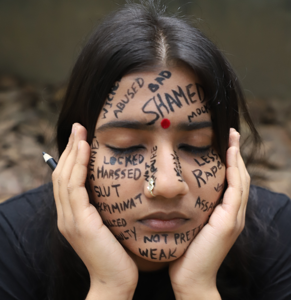 Photo Of Young Southeast Asian Woman With Her Head In Her Hands With Abusive Words Written Across Her Face, For Examples Bad And Shamed