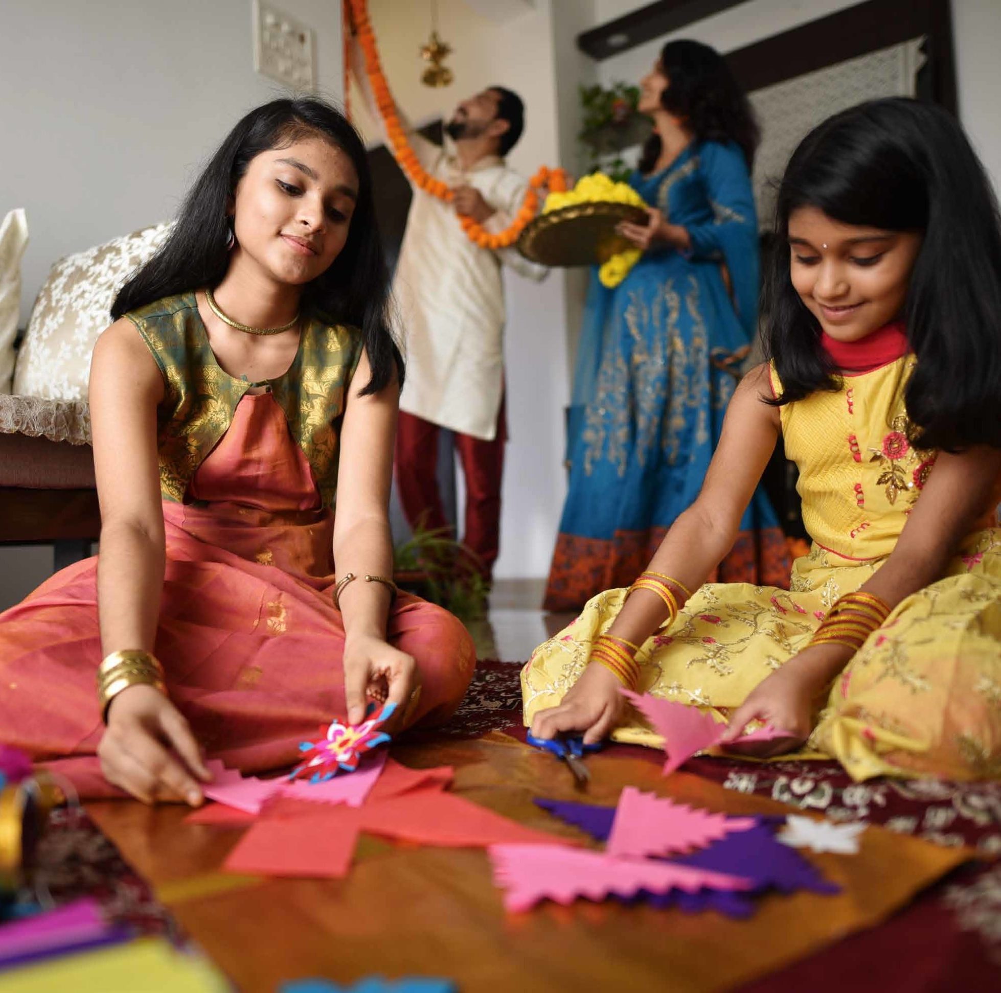 Indian Man, Woman And Two Girls Decorating Their House