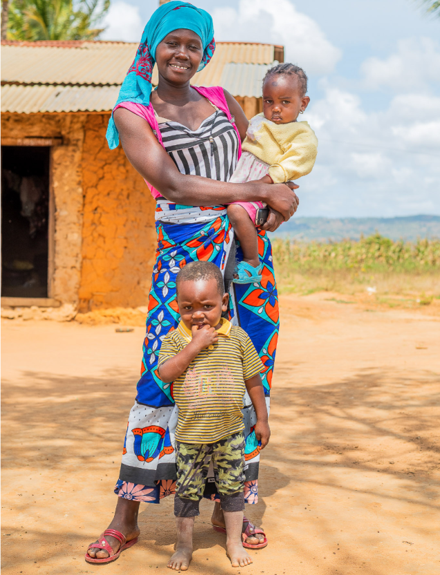 A Black Woman With Two Children. She's Holding One On Her Hip And The Other One Is Standing In Front Of Her.